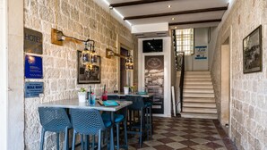 A restaurant with stone walls, checkered flooring, and blue bar stools. - Hotel Sikaa (Trogir)