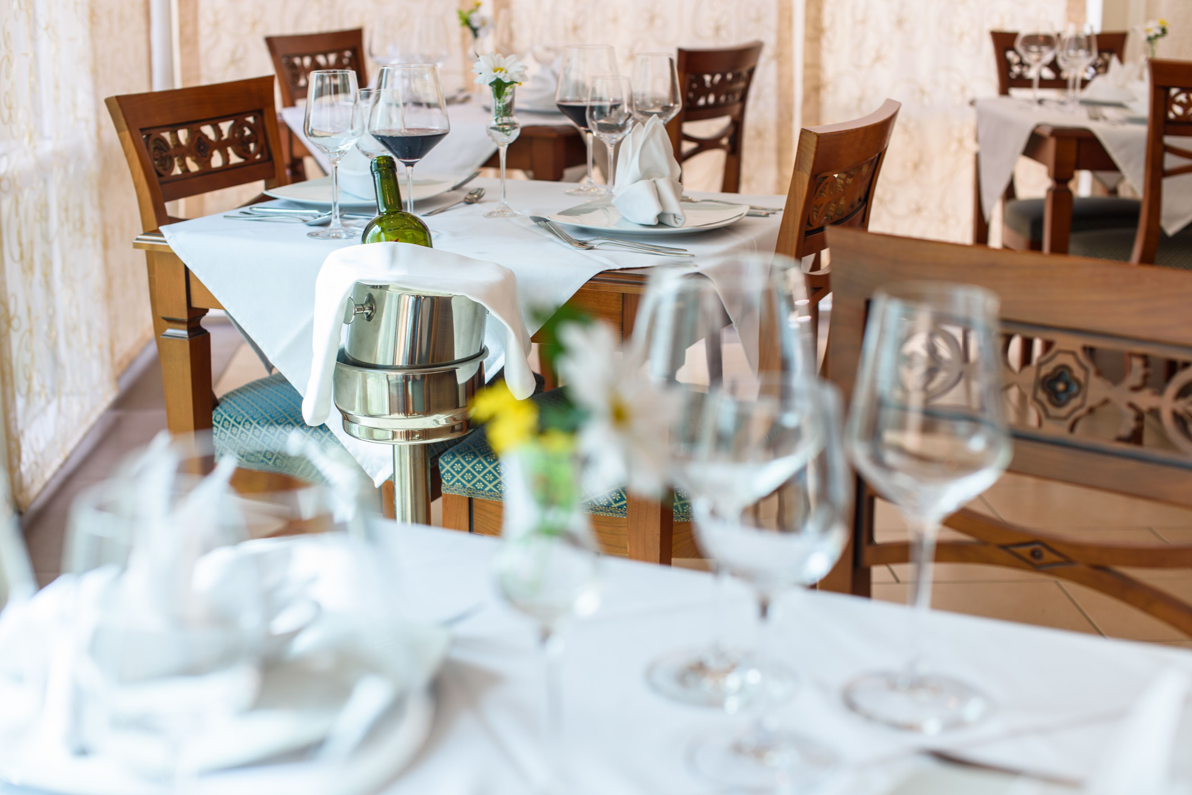 A dining table set with wine glasses, a bottle, and a silver pitcher.