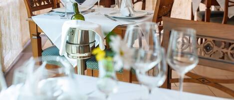 A dining table set with wine glasses, a bottle, and a silver pitcher.