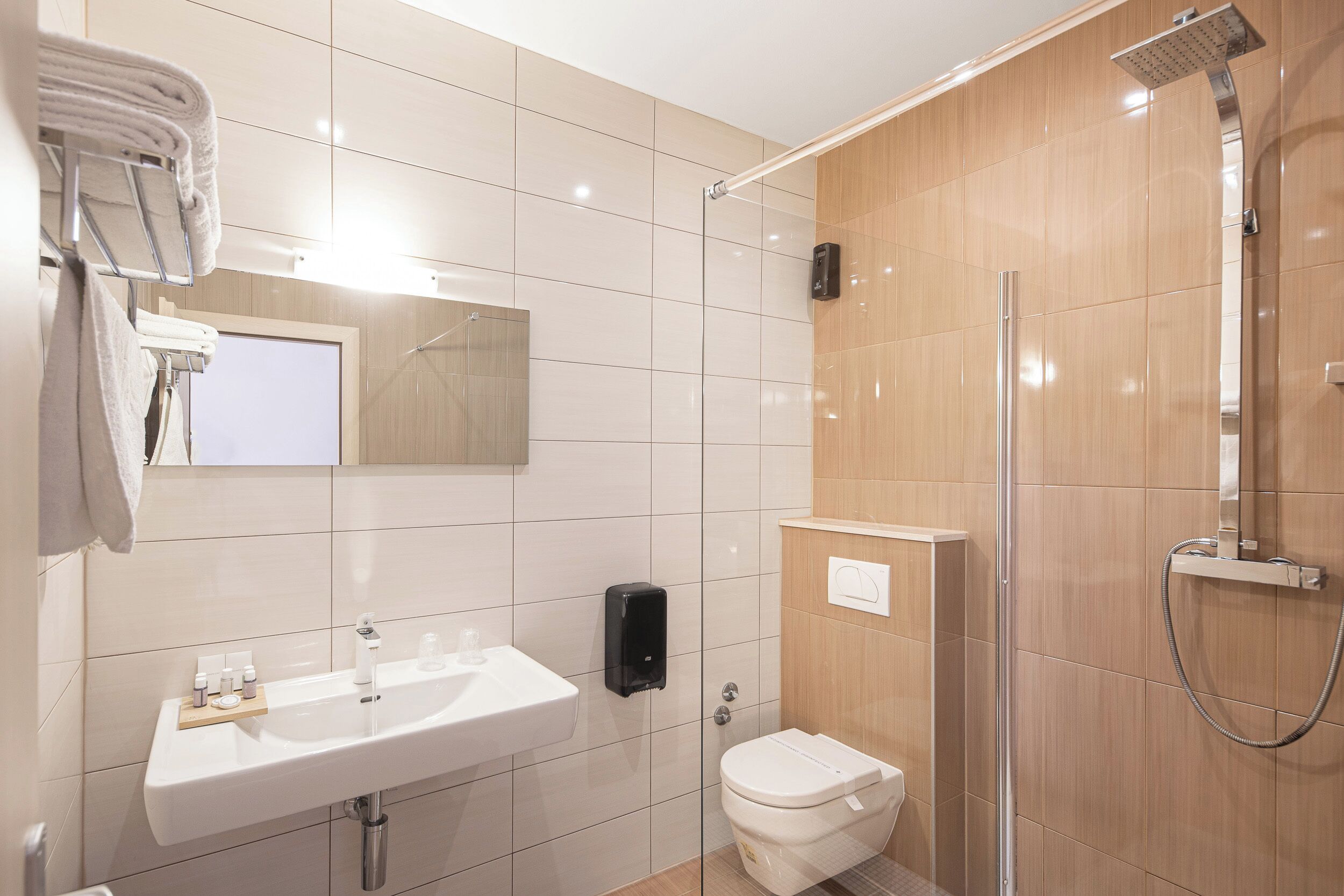 Un baño moderno con lavamanos blanco, inodoro y zona de ducha con mampara de vidrio.
