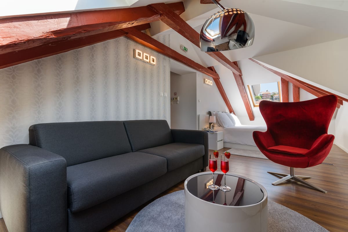 A modern living room with a dark grey sofa, a red chair, and a glass coffee table with two red drinks.