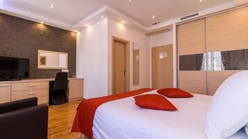 Una habitación de hotel moderna con una cama grande, un escritorio con silla, televisión y armario.