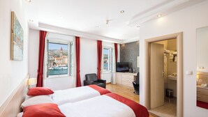 A hotel room with two beds, a TV, a desk, and a bathroom. - Hotel Sikaa (Trogir)