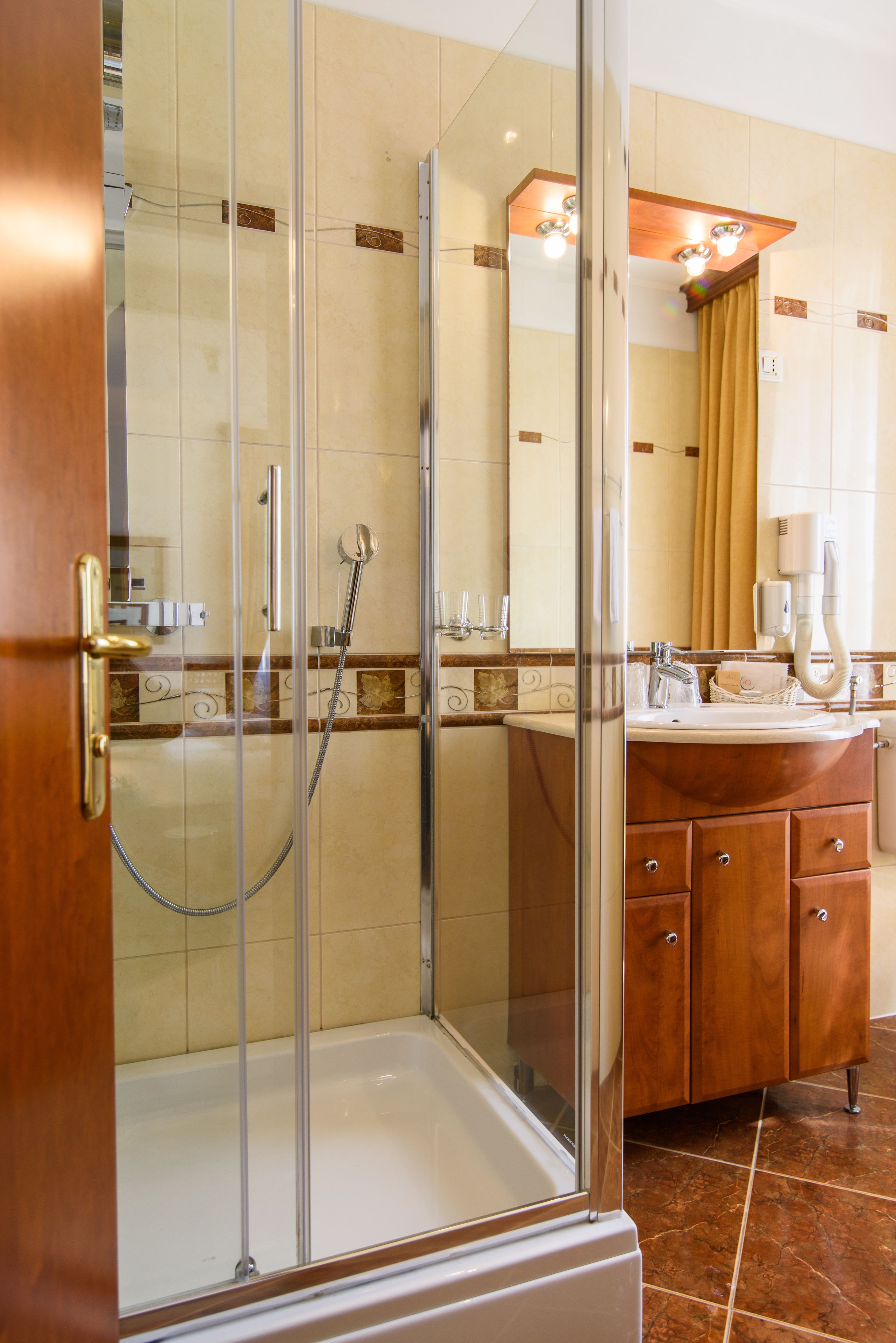 Een moderne badkamer met een douchecabine van glas, een houten wastafelmeubel en een grote spiegel.