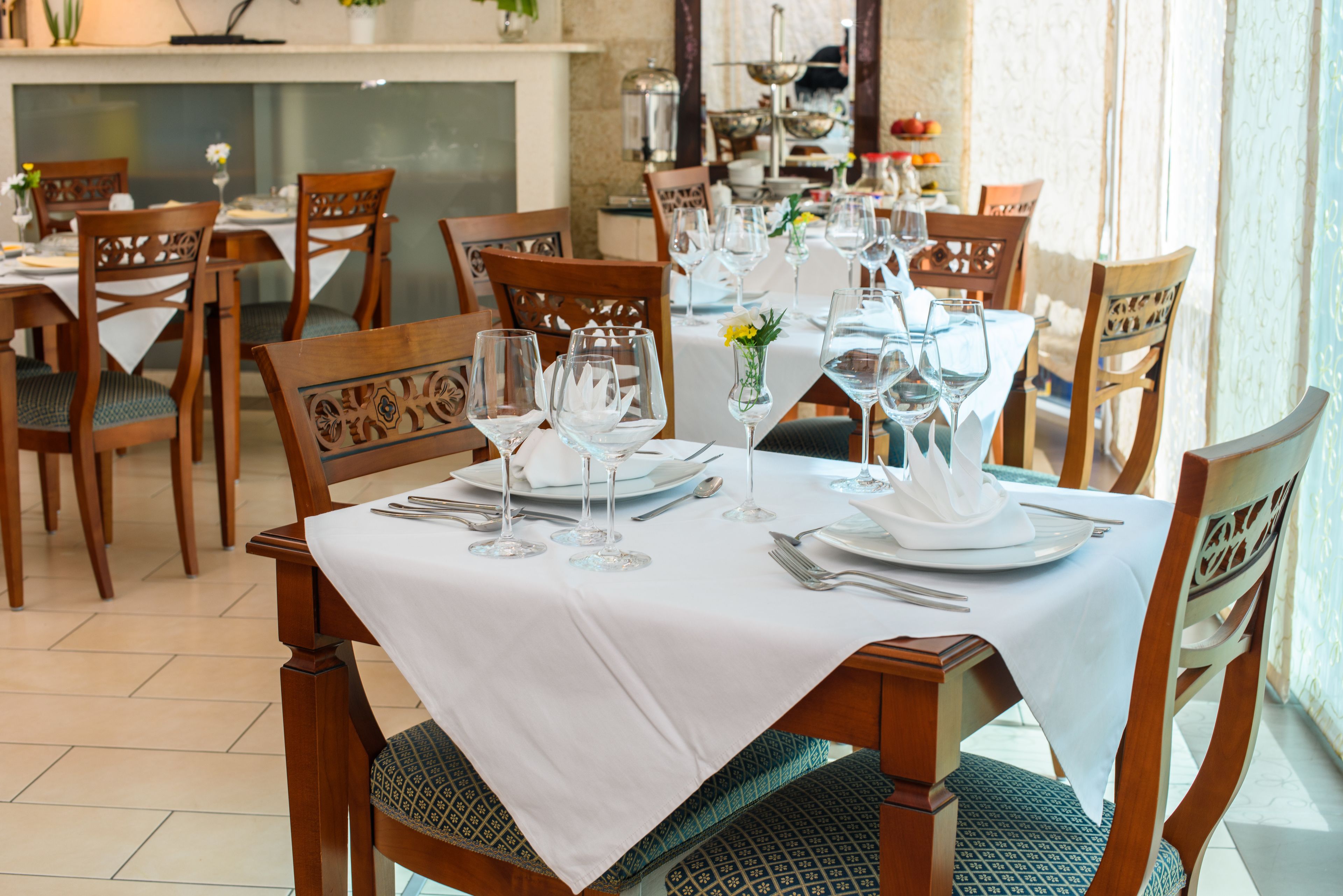 A dining area with a table set for six, surrounded by wooden chairs with intricate back designs.