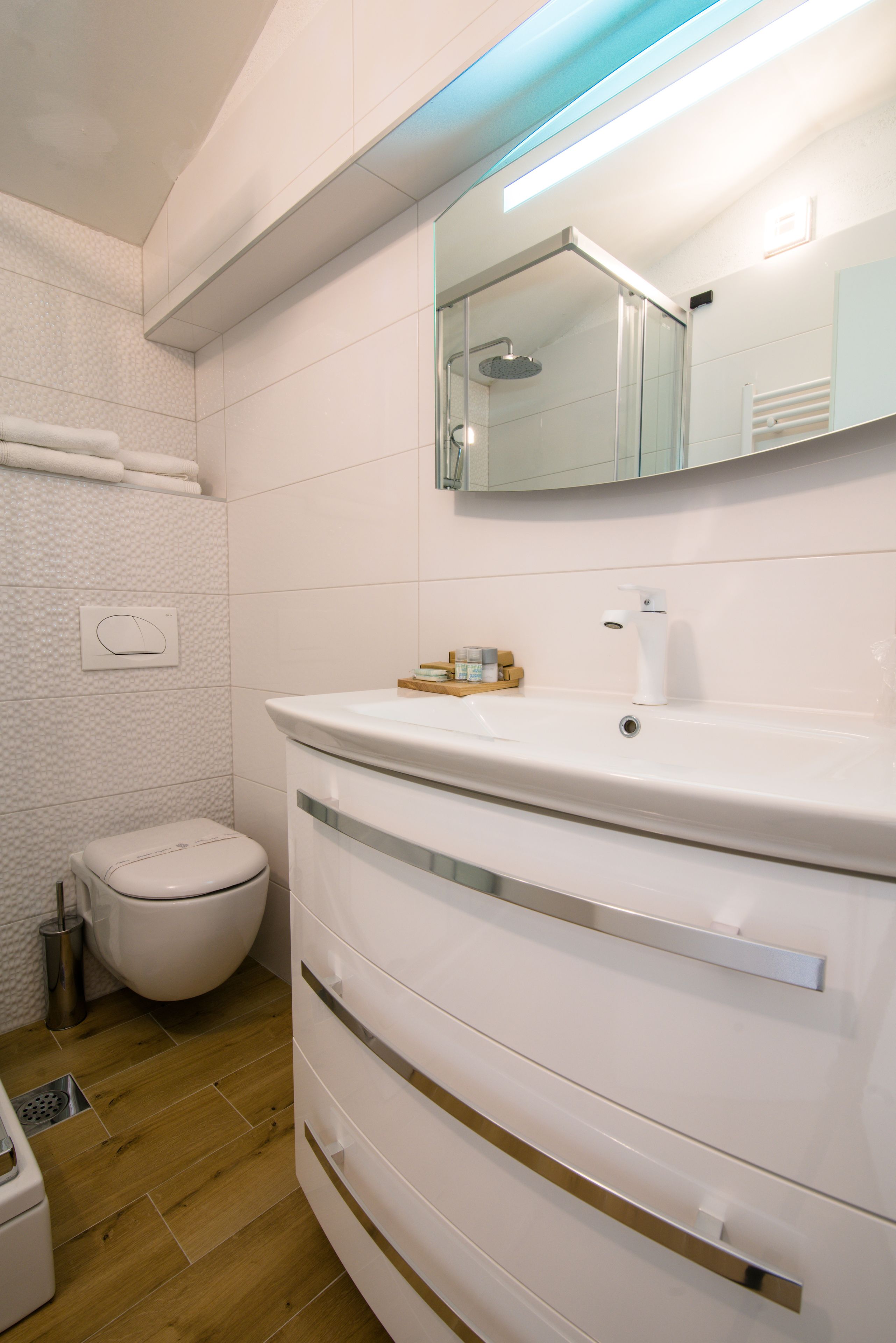 A modern bathroom with a white vanity, a toilet, and a shower area.