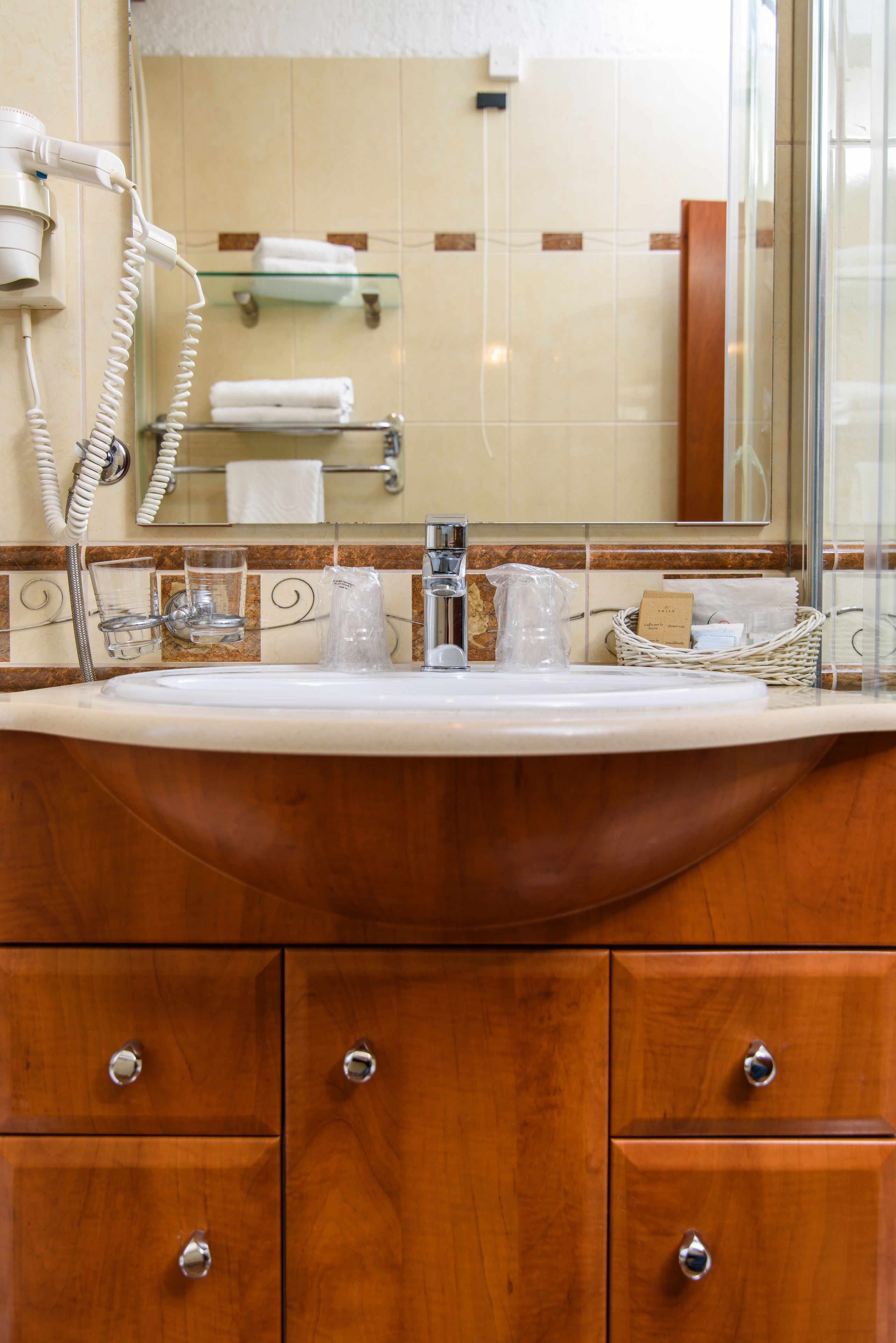 A bathroom with a wooden vanity, a glass shower enclosure, and a mirror above the sink.
