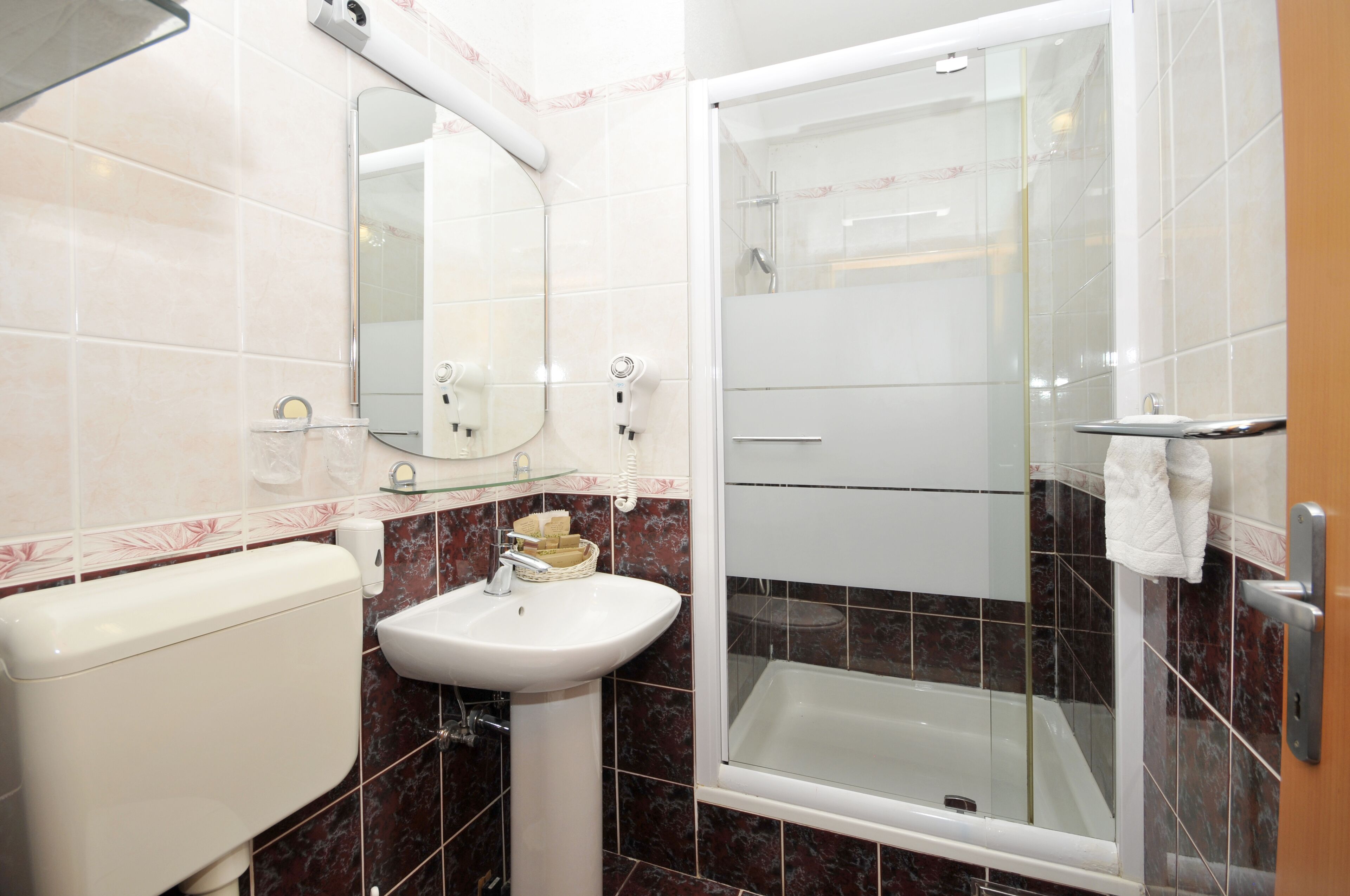 Ein Badezimmer mit Toilette, Waschbecken, Spiegel und einer Duschkabine.