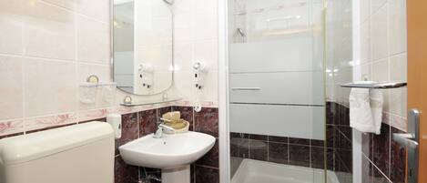 Ein Badezimmer mit Toilette, Waschbecken, Spiegel und einer Duschkabine.