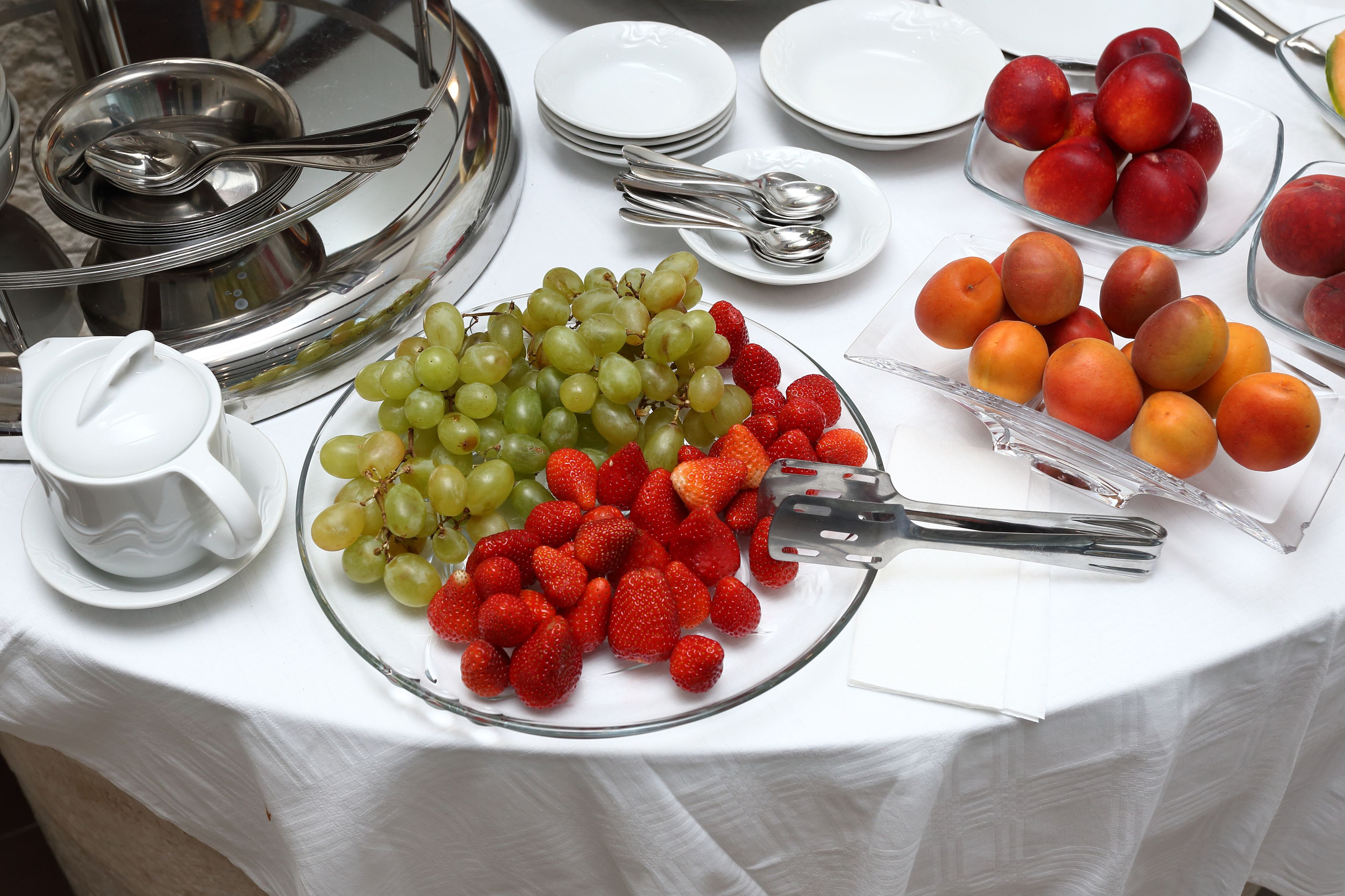 A buffet table with various fruits and utensils.
