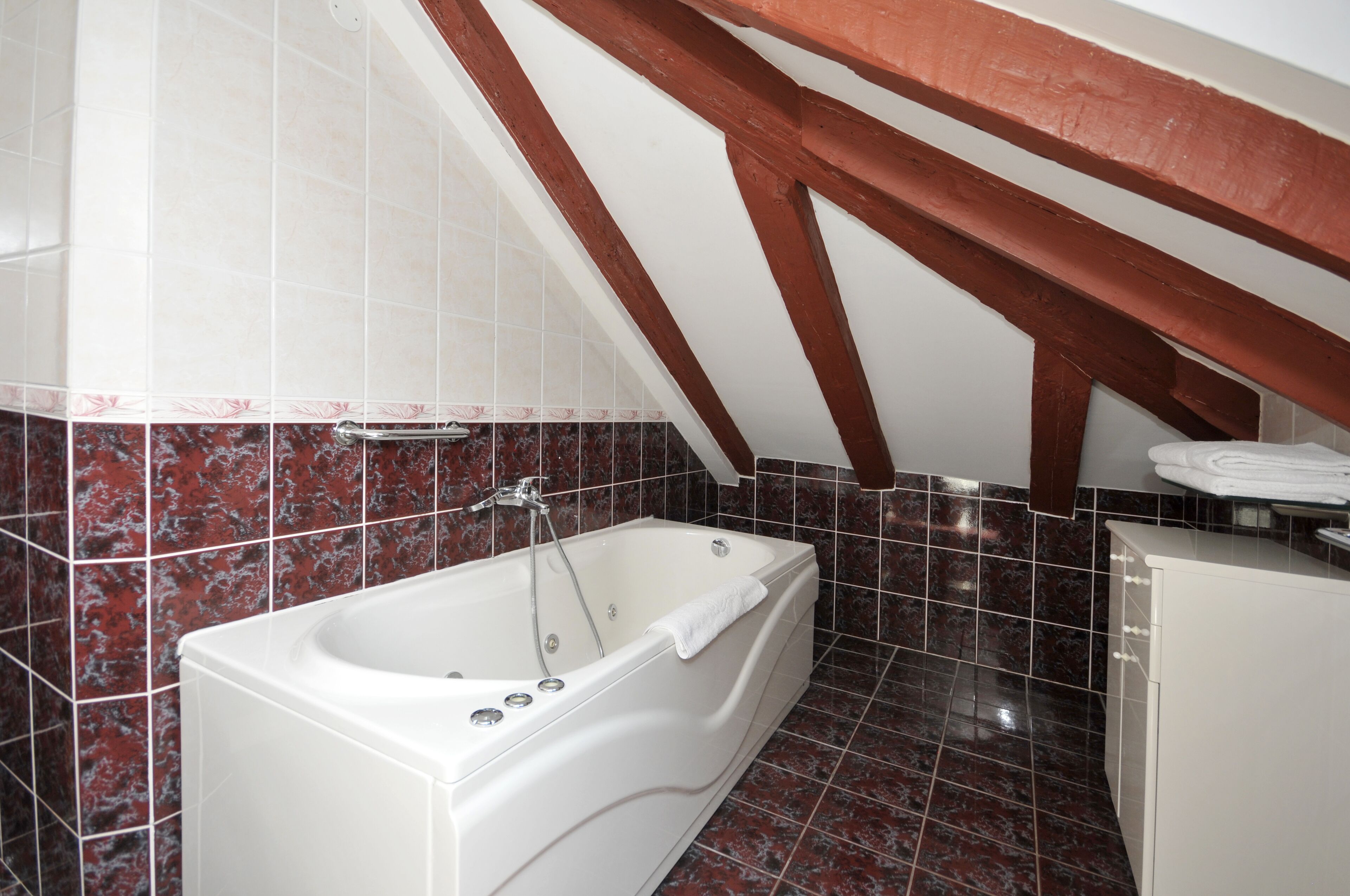 A bathroom with a bathtub, white tiles, and a red-tiled floor.