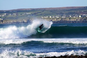 Un surfista montando una ola, con un pueblo costero al fondo.
