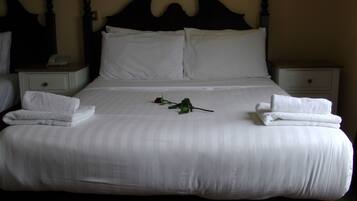 A neatly made bed with white linens and two folded towels on each side.
