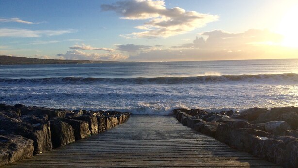 A wooden boardwalk leading to the ocean with waves crashing onto the shore. - Shamrock Inn Hotel (Lahinch)