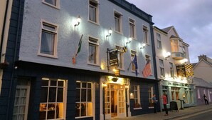 Un hotel con bar y restaurante en la planta baja, con varias banderas y señalización iluminada.