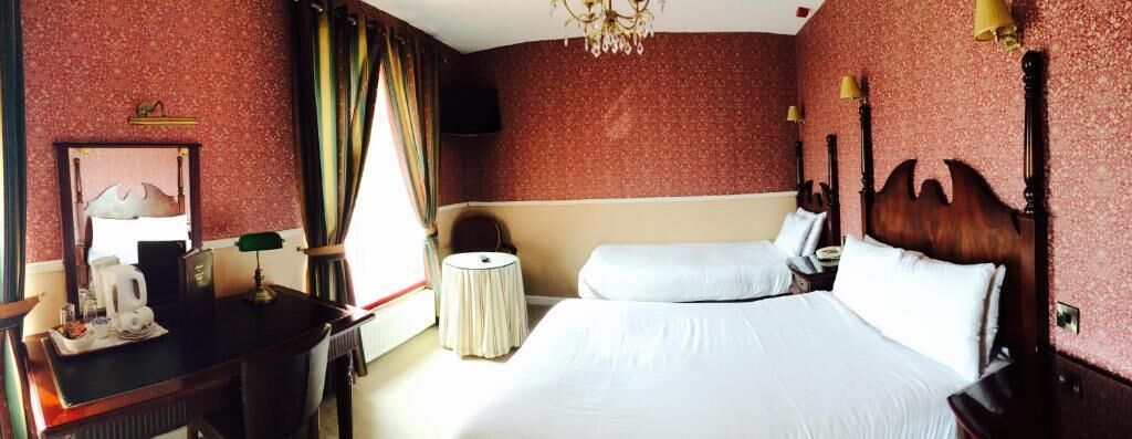 Een hotelkamer met een groot bed, een nachtkastje, een stoel, een klein rond tafeltje en een spiegel.