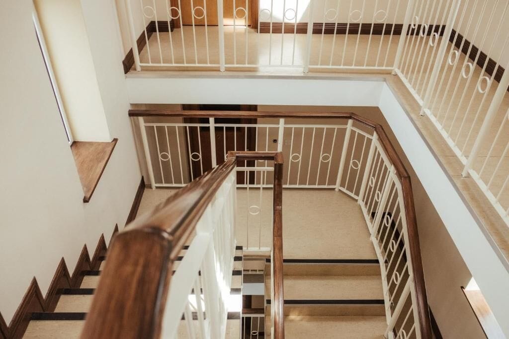 Ein mehrgeschossiges Interieur mit einer Holztreppe und weißen Geländern.