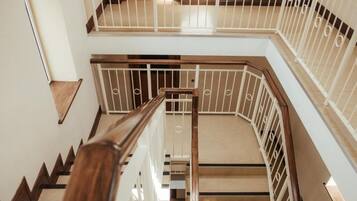 Ein mehrgeschossiges Interieur mit einer Holztreppe und weißen Geländern.
