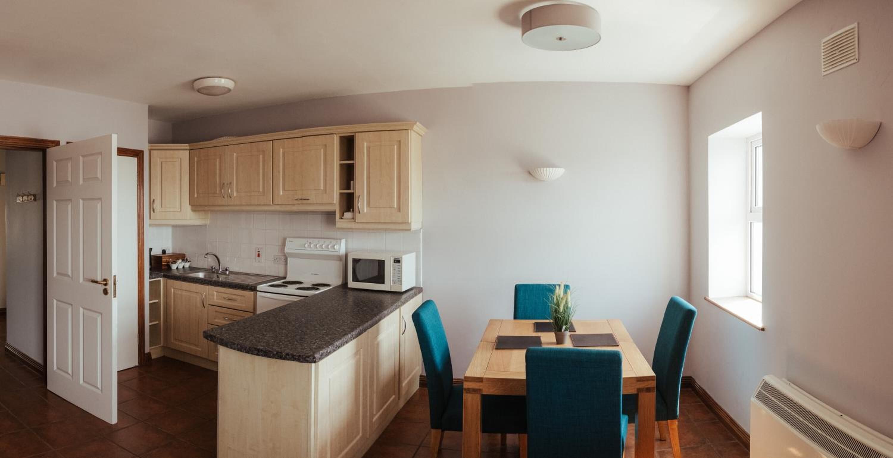 A kitchen with wooden cabinets, a stove, a microwave, and a dining table with chairs.