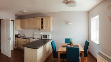 A kitchen with wooden cabinets, a stove, a microwave, and a dining table with chairs.