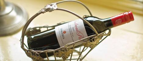 A bottle of wine in a decorative wire basket.