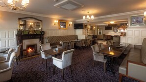 Un vestíbulo de hotel con chimenea, zonas de estar y un bar.