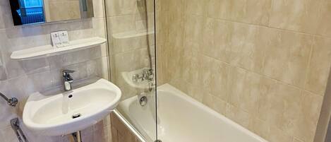 A bathroom with a glass-enclosed shower, a sink, and a bathtub.