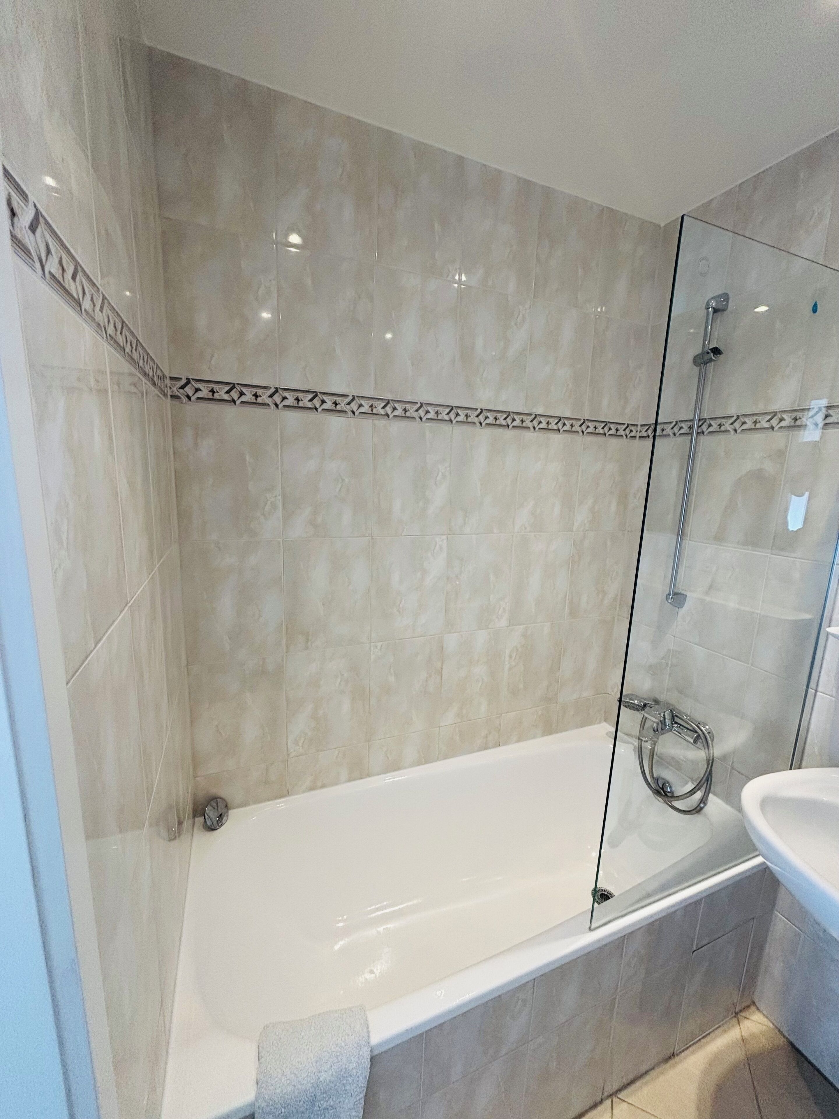A modern bathroom with a glass-enclosed shower, a white bathtub, and a sink.