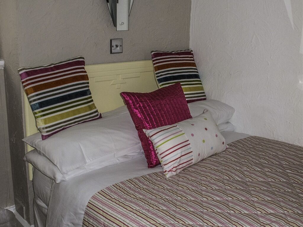 A bed with striped bedding and multiple pillows, including a pink one.
