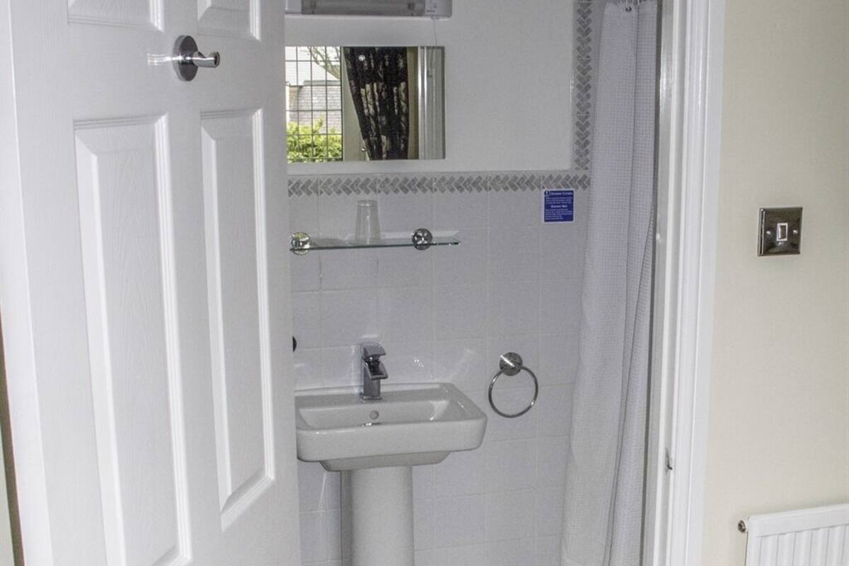 A bathroom with a white sink, a mirror above it, and a shower curtain.