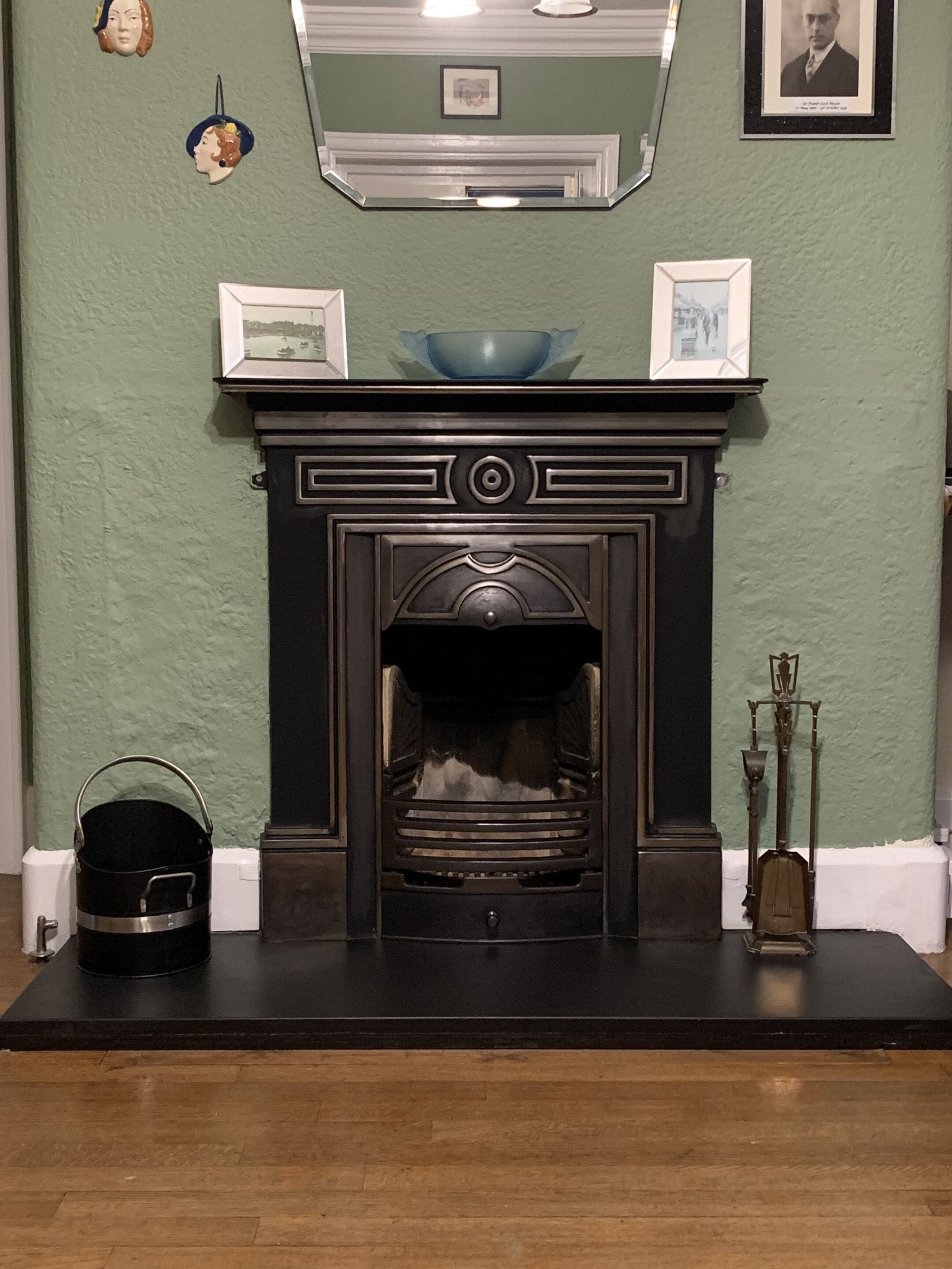 A fireplace with a black mantel, a framed picture above it, and a decorative bowl on top.