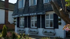 Kaksikerroksinen rakennus, jonka kyltissä lukee: ”The White Lodge 80250”.