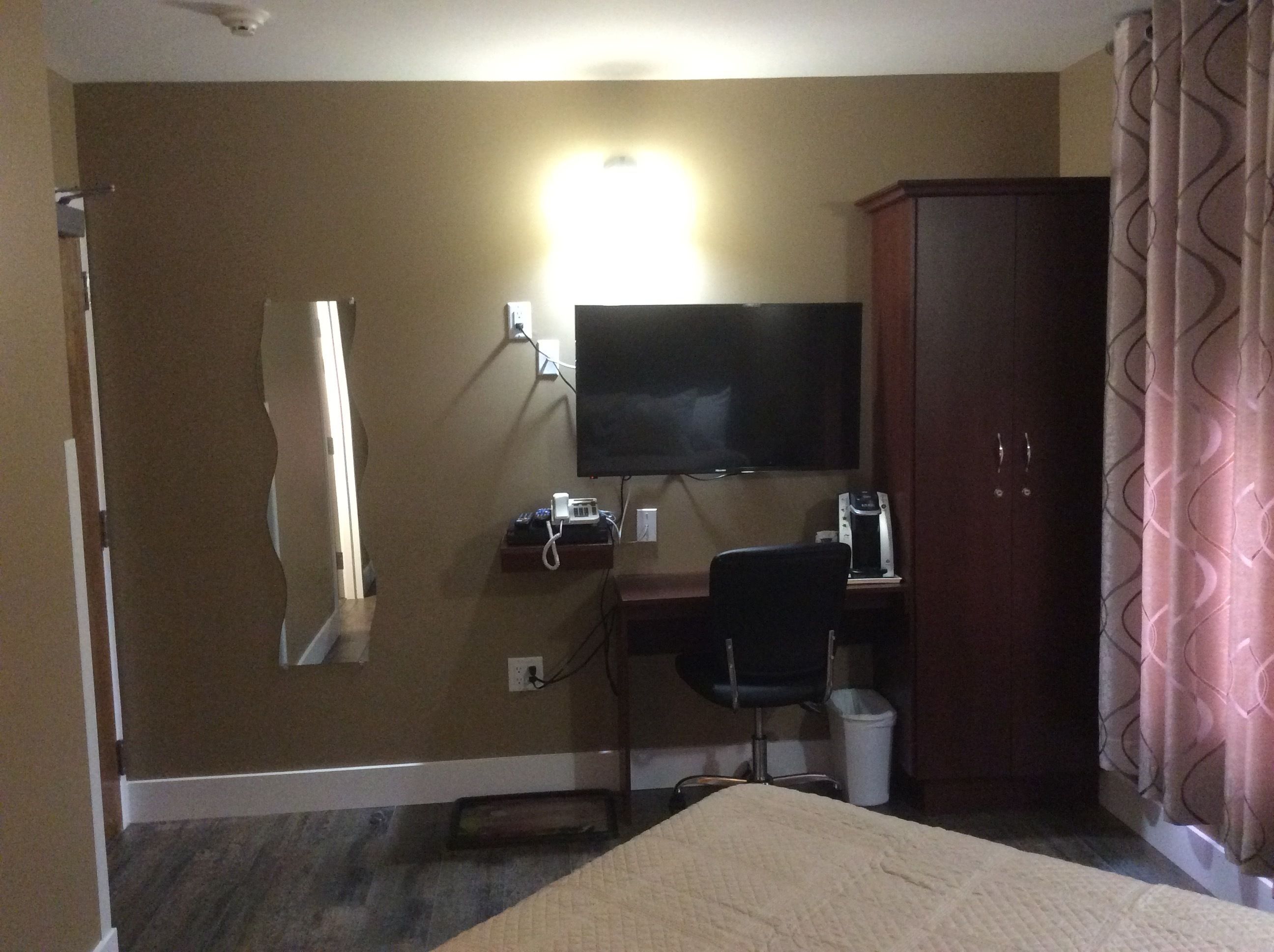 Une chambre d’h ôtel comprenant un lit, un bureau avec une chaise, un téléviseur fixé au mur, une armoire et une salle de bain.