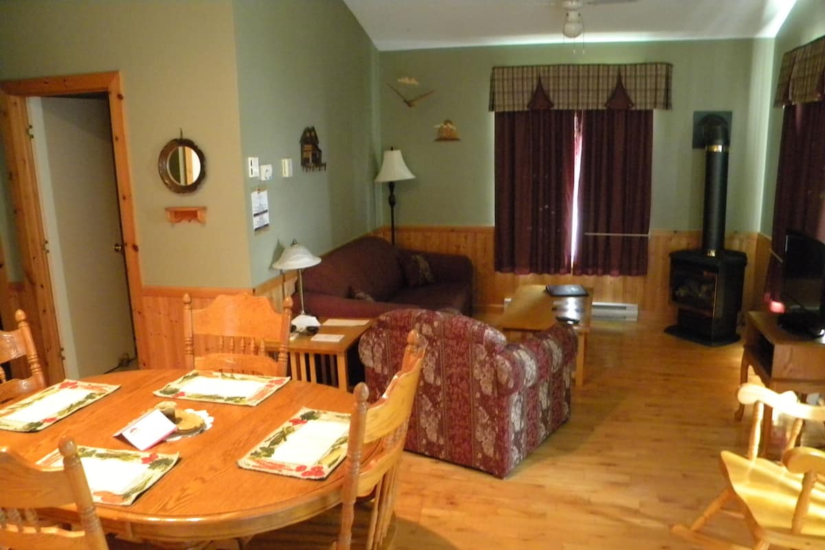 Een gezellige woonkamer met een eettafel voor vier personen, een bank, een open haard en een televisie.