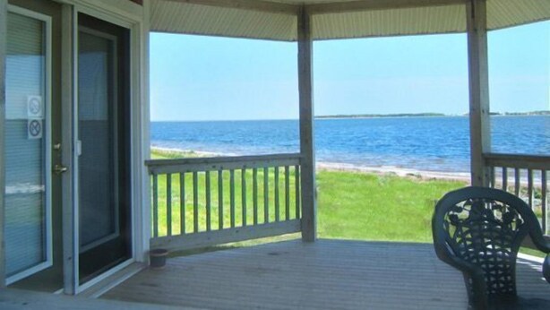 A covered porch with a view of the ocean.