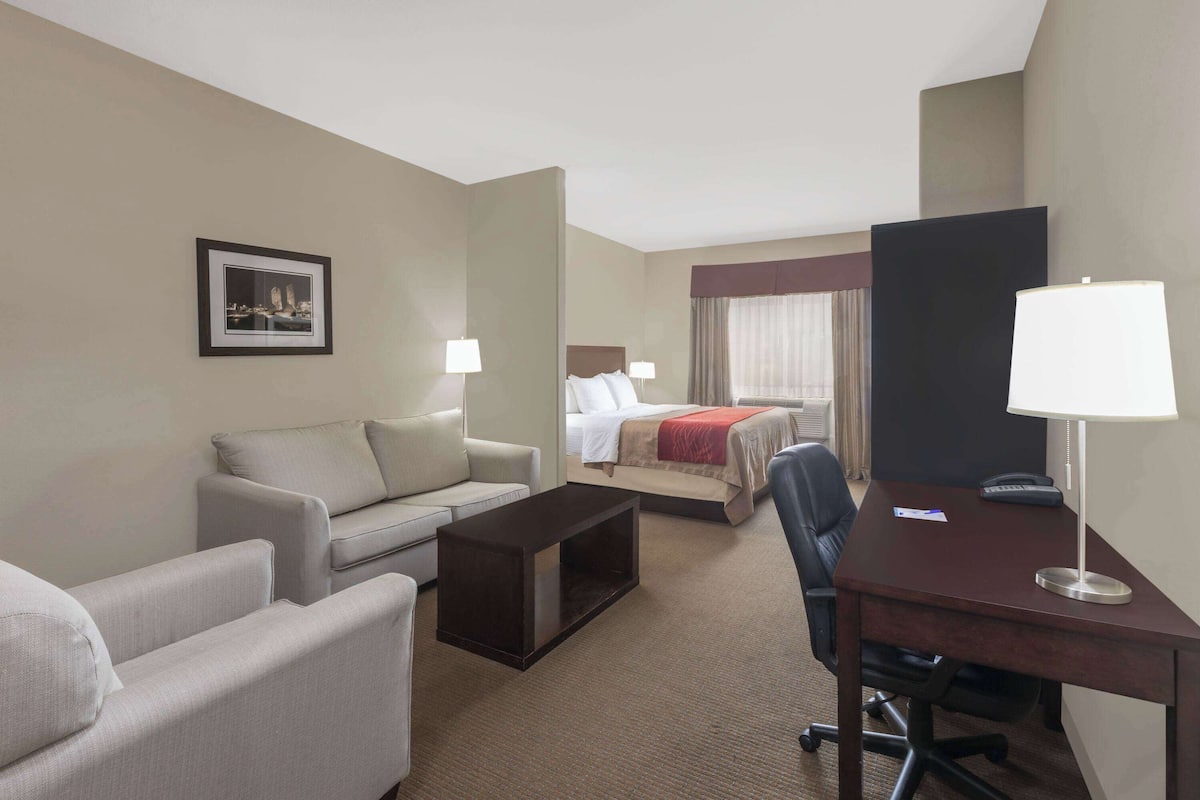 Ein Hotelzimmer mit Bett, Schreibtisch, Stuhl, Sofa und Couchtisch.