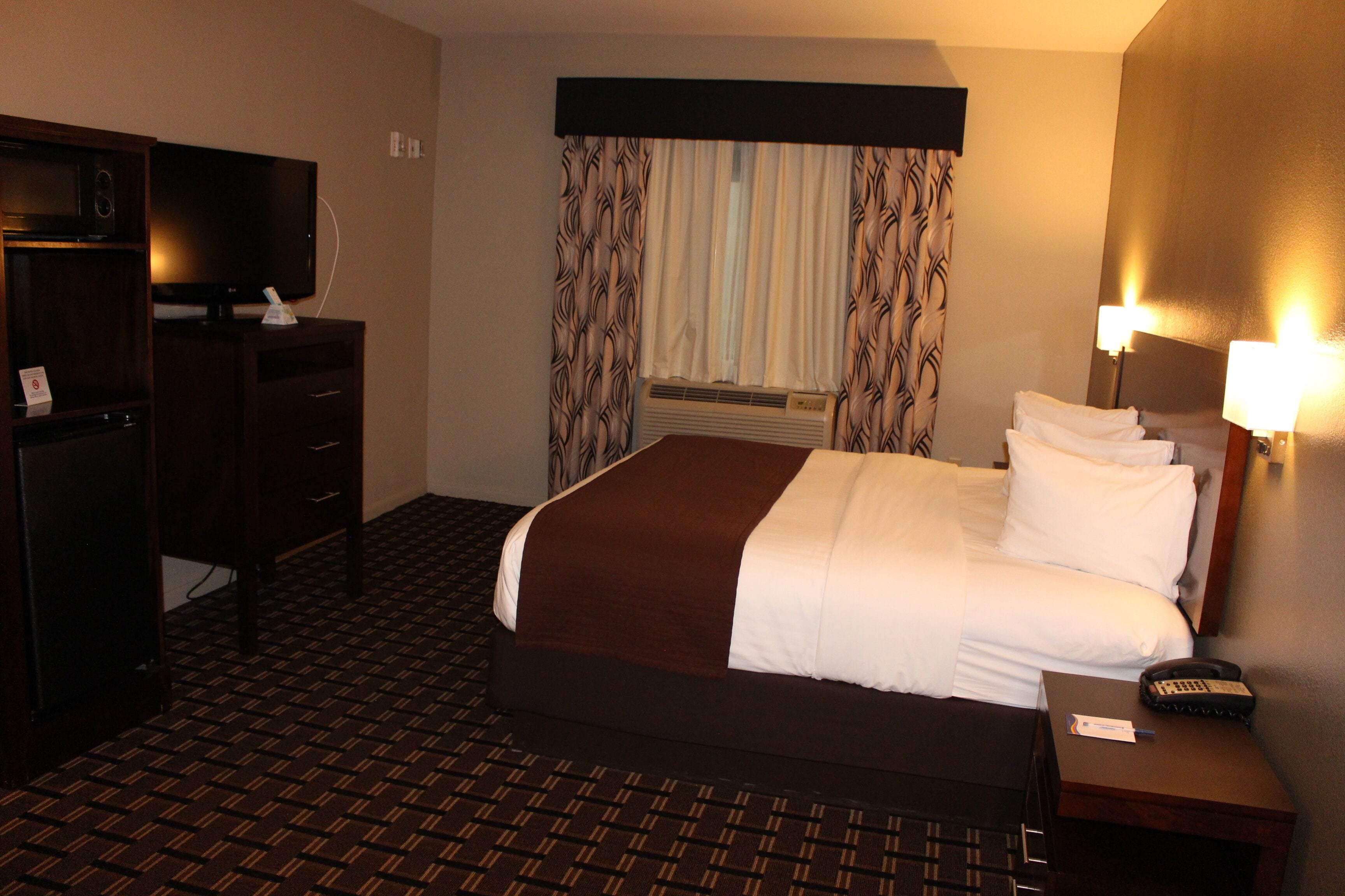 A hotel room with a bed, a television, a desk, and a nightstand.