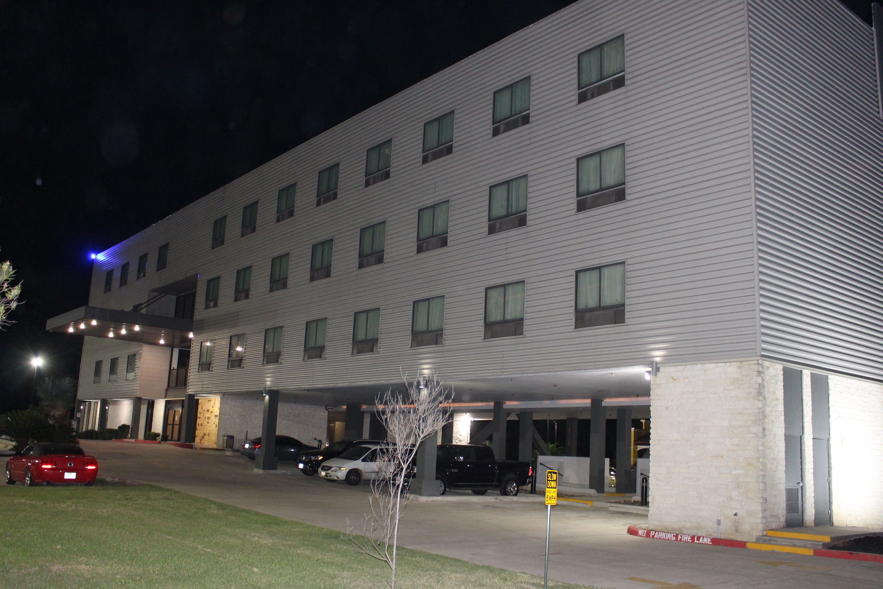 A multi-story hotel with a parking garage and a covered walkway.