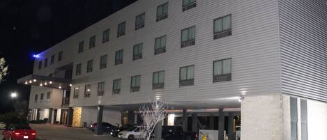 A multi-story hotel with a parking garage and a covered walkway.