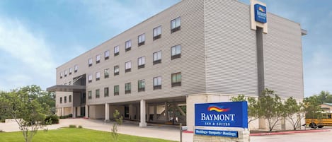 A Baymont Inn & Suites building with a sign indicating it offers weddings, banquets, and meetings.