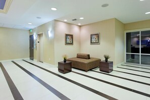 A lobby with a reception desk, a seating area with a sofa and two side tables, and a large window. - Holiday Inn Express Benicia by IHG (Benicia)