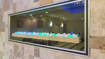 Una ventana enmarcada con el reflejo de una habitación que contiene una fila de objetos blancos y azules sobre una estantería.