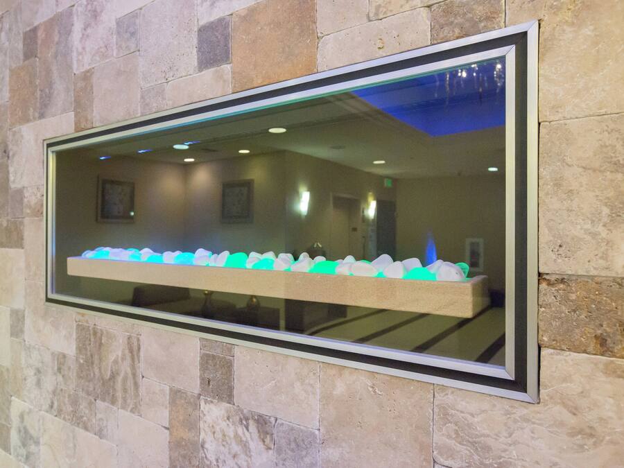 Una ventana enmarcada con el reflejo de una habitación que contiene una fila de objetos blancos y azules sobre una estantería.
