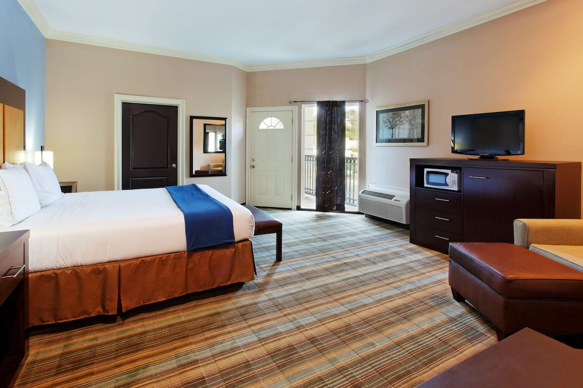A hotel room with a large bed, a flat-screen TV, a desk, and a chair.