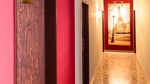 Un corridoio di un hotel con una porta rossa, una targa con il numero e un poster della Torre Eiffel.