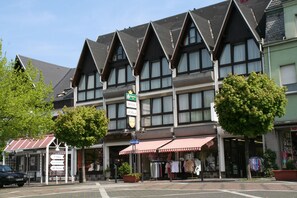 Un hotel de estilo arquitectónico tradicional, con un letrero llamativo y un toldo rojo y blanco.