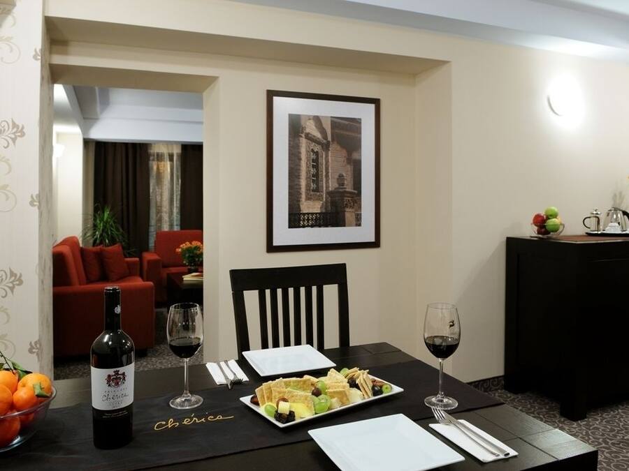 Comedor con una mesa dispuesta para dos personas, una botella de vino y un frutero.