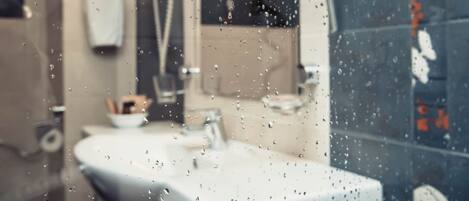 A bathroom with a sink, mirror, and towel dispenser.