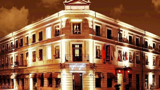 Un hotel histórico con un estilo arquitectónico europeo clásico, que presenta una fachada simétrica, varios balcones y una entrada destacada.