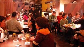 Un restaurante concurrido con mesas, sillas, una barra y un candelabro.